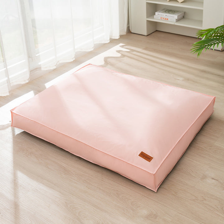 Pink mattress on a wooden floor with a white curtain in the background