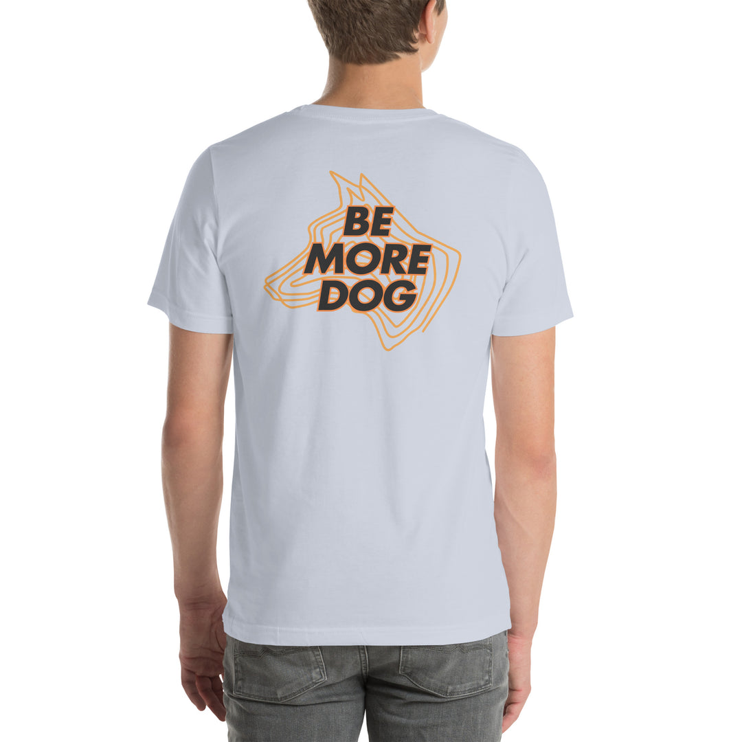 Person wearing a light gray t-shirt with 'Be More Dog' print on the back, standing against a white background.