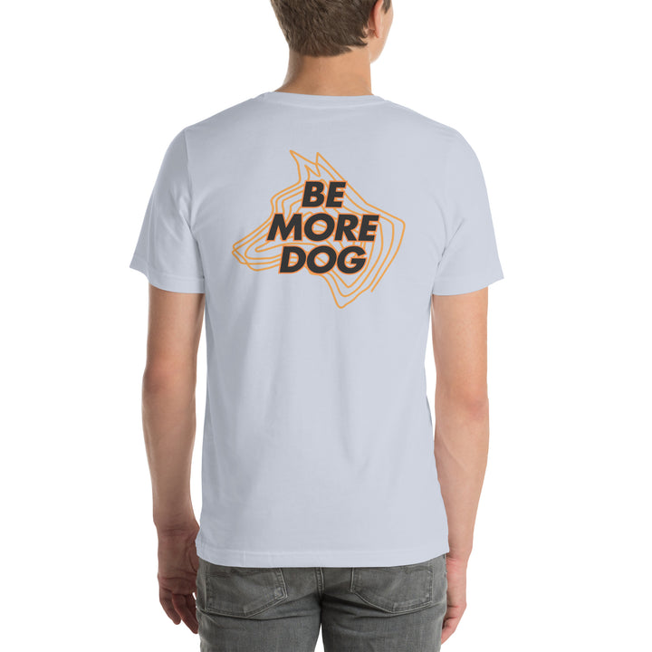Person wearing a light gray t-shirt with 'Be More Dog' print on the back, standing against a white background.